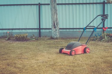 Yazlık bahçesinde çimenlerin üzerinde yeşil çim/biçme çimenlikte çim biçme makinesi. Tonda