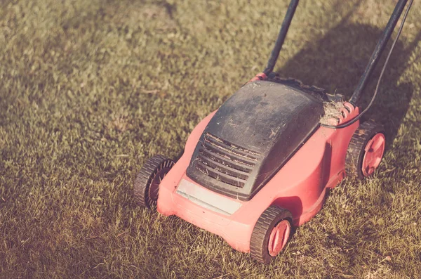 lawn mower on the lawn/red lawn mower on summer meadow. Toned and copyspace