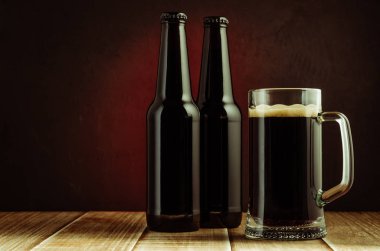 kırmızı arka plan/siyah şişe ve bardak bira bir ahşap raf kırmızı bir arka plan üzerinde siyah şişe ve bardak bira. Boşaltmak ve seçici odak