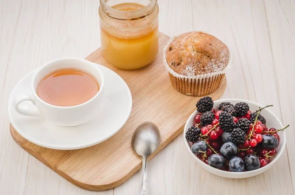 breakfast: tea with fresh berries, cake and honey/healthy breakfast: tea with fresh berries, cake and honey on a wooden surface. Top view