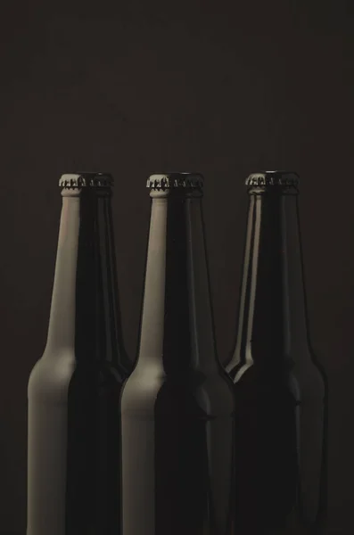Three black bottles of beer on a dark background/Three black bottles of beer on a dark background, selective focus