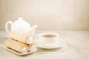 bir tübül ile beyaz krema ve çay fincan beyaz mermer masaya pasta / çay içme ile beyaz mermer masada kremalı kek. Seçici odak