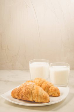 Kahvaltı croissants ve gözlük süt/taze kruvasanlar ve süt beyaz bir arka plan üzerinde bardak. Seçici odak
