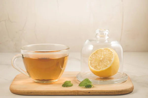 tea with a lemon and mint/tea with a lemon and mint on a wooden tray on a white stone background. Selective focus