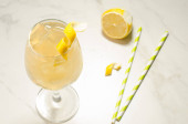 koktejl s ledem a citronem/koktejl s ledem, brčka a citron na bílém mramoru. Pohled shora