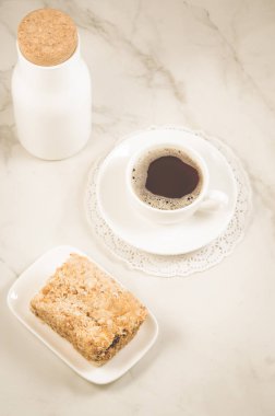 kahvaltı kahve ile ve bir tatlı/şişe, kahve fincanı ve tatlı bir beyaz mermer tablo. Üstten görünüm