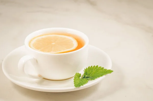 tea cup with a lemon and mint/tea cup with a lemon and mint on a white marble table, selective focus