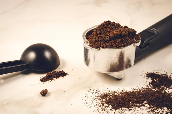 holder filled with ground coffee a black spoon/holder filled with ground coffee a black spoon on a marble background. Selective focus