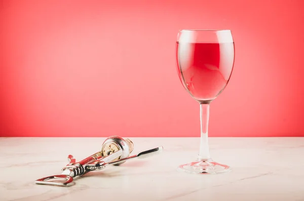 Wine glass and corkscrew on pink background/Wine glass and corkscrew on pink  background. Selective focus and copyspace