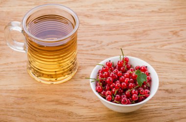 bir bardak çay ve kırmızı frenk üzümü/bardak çay ve bir ahşap zemin üzerine kırmızı kuş üzümü. Üstten görünüm