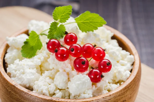 cottage cheese with red currant in a wooden plate/cottage cheese with red currant in a wooden plate. Close up