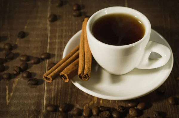 white cup with coffee and cinnamon on a dark wooden background/white cup with coffee and cinnamon on a dark wooden background. Top view