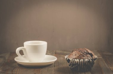 kahve fincanı ve bir fincan çikolatalı muffin/kahve ve koyu ahşap bir masa üzerinde bir çikolatalı kek.
