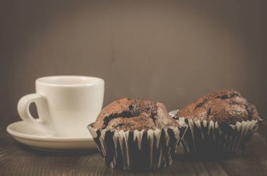 kahve fincanı ve iki çikolatalı muffin/kahve fincanı ve karanlık bir arka plan, seçici odak üzerinde iki çikolata kek