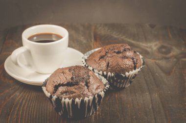 kahve fincanı ve iki çikolatalı muffin/kahve fincanı ve ahşap bir masa, seçici odak üzerinde iki çikolatalı kek