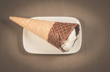 dondurma koni çikolata beyaz tabakta üstten görünüm ile çikolata üzerinde beyaz plaka/Ice cream koni ile