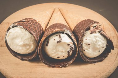 Üç dondurma koni çikolata yuvarlak ahşap destek, seçici odak ile içinde çikolata/üç dondurma koni ile