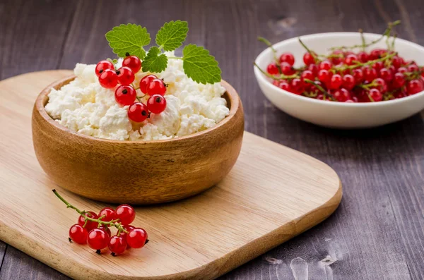 breakfast: cottage cheese with red berries and mint in a wooden bowl/breakfast: cottage cheese with red berries and mint in a wooden bowl. selective focus