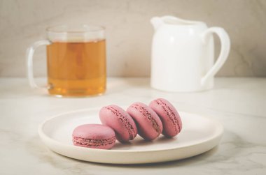 tatlı macaroons veya macaron ve üzerinde beyaz bir backgro bir bardak çay