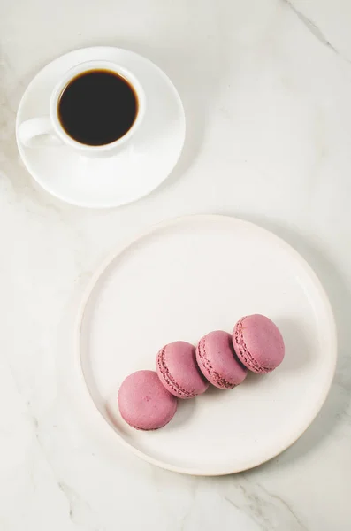 Sweet macaroons or macaron in a white bowl and coffee cup on a w — Stock Photo, Image