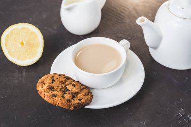 Beyaz bardakta çay, limon ve sütlü kahvaltı, beyaz bardakta çay, limon ve sütlü koyu bir masa.