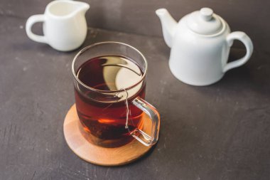 Ahşap destekli çay, siyah masada çaydanlık ve krema, tahta destekli çay, siyah masada beyaz çaydanlık ve krema. Üst görünüm.