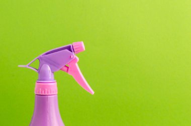 Şişedeki sprey hortumu / yeşil arka plandaki bir şişedeki mor sprey hortumu. Boşluğu kopyala.