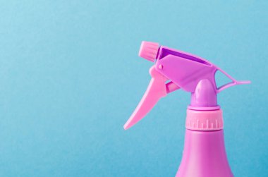 Şişedeki sprey hortumu / mor sprey hortumunu mavi arka plandaki bir şişeye sıkın. Boşluğu kopyala.