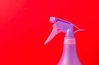 Şişeye sprey sıkın / Kırmızı arka plandaki bir şişeye mor sprey sıkın.