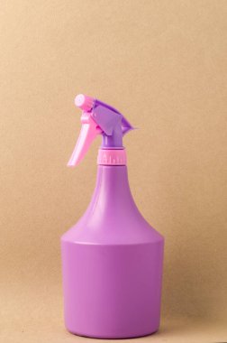 Açık kahverengi arka planda spreyli şişe / açık kahverengi arka planda izole edilmiş mor sprey şişe