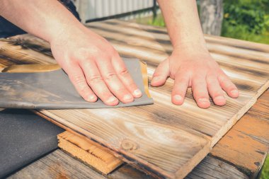 Tahta bir yüzey / insanın eli zımpara kağıdıyla ahşap bir yüzey işliyor.