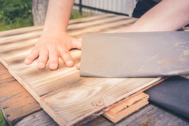 Tahta bir yüzey / insanın eli zımpara kağıdıyla ahşap bir yüzey işliyor.