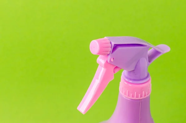 spray nozzle on a bottle/purple spray nozzle on a bottle on a green background. Copy space.