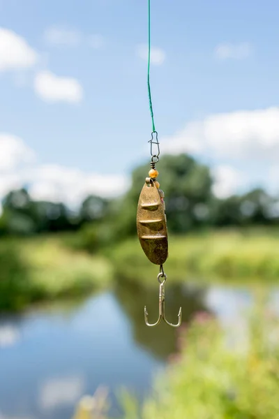 shine for fishing hangs/metal bait for fishing on the background of the river.