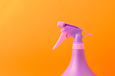 Şişedeki sprey hortumu / turuncu arka plandaki bir şişedeki mor sprey hortumu. Boşluğu kopyala.