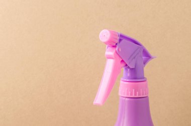 Şişedeki sprey hortumu / açık kahverengi arka plandaki bir şişedeki mor sprey hortumu. Boşluğu kopyala