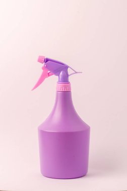 Açık pembe arka planda spreyli şişe / açık pembe arka planda izole edilmiş mor sprey şişesi