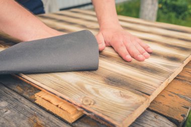 Tahta bir yüzey / insanın eli zımpara kağıdıyla ahşap bir yüzey işliyor.