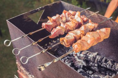 Güneşli bir günde et ızgara ve ızgara yapmak için şişlenmiş et.