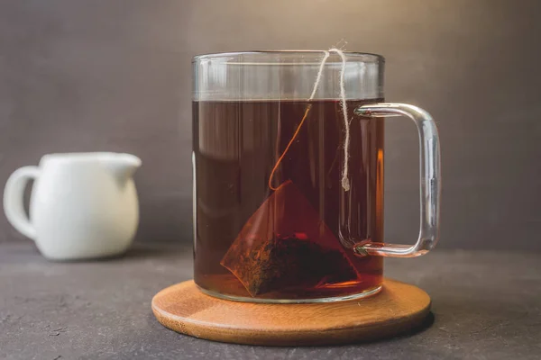 Tasse Tee Auf Holzunterlage Und Milchkännchen Auf Schwarzem Tisch Tasse — Stockfoto