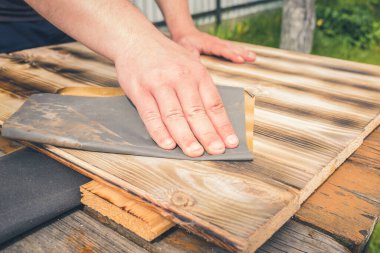 Tahta bir yüzey / insanın eli zımpara kağıdıyla ahşap bir yüzey işliyor.