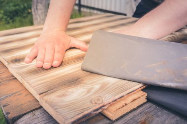 Tahta bir yüzey / insanın eli zımpara kağıdıyla ahşap bir yüzey işliyor.