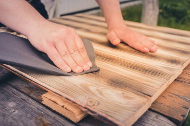 Tahta bir yüzey / insanın eli zımpara kağıdıyla ahşap bir yüzey işliyor.