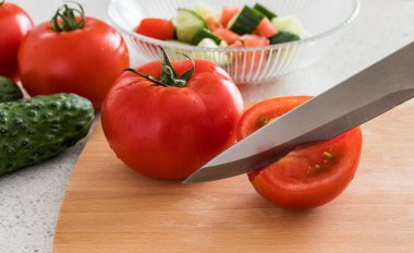 Mutfakta salatası yapma. Domates ve salatalık, ahşap levha ve bıçak