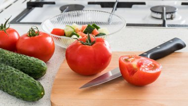 Mutfakta salatası yapma. Domates ve salatalık, ahşap levha ve bıçak