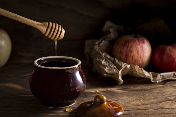 Honey background. Honey in pot with apples . On a brown wooden board.