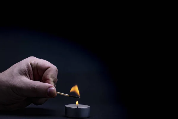 Man hand with Matchstick light flame on candle in candlestick, close up