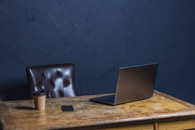 Masanın üstüne boş dizüstü kadar alay. Ahşap masa siyah duvar arka plan üzerinde kişisel dizüstü bilgisayar.