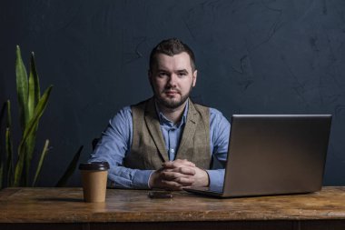 Genç işadamı ahşap masa üstünde onun laptop üzerinde çalışıyor. Metin için yer. Koyu arka plan. Metin için yer