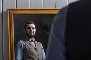 Damat aynaya bakıyor ve papyona dokunuyor.